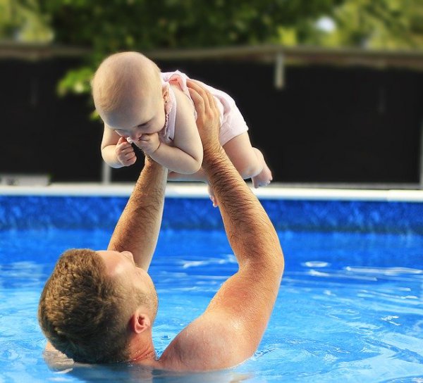 Papa mit Kleinkind im Pool eines Kinderhotels in Österreich